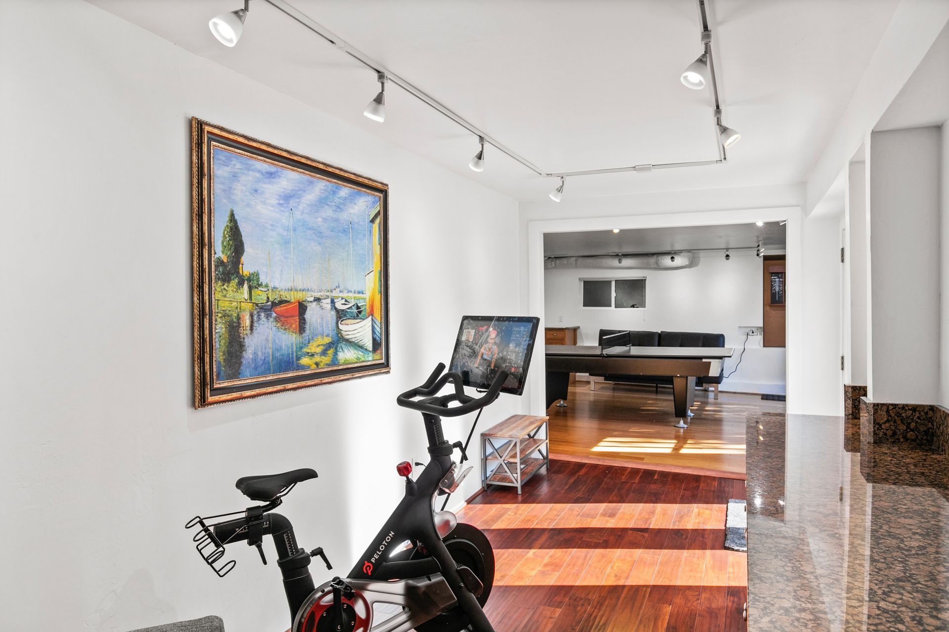 A bicycle is parked in a room with a painting on the wall.
