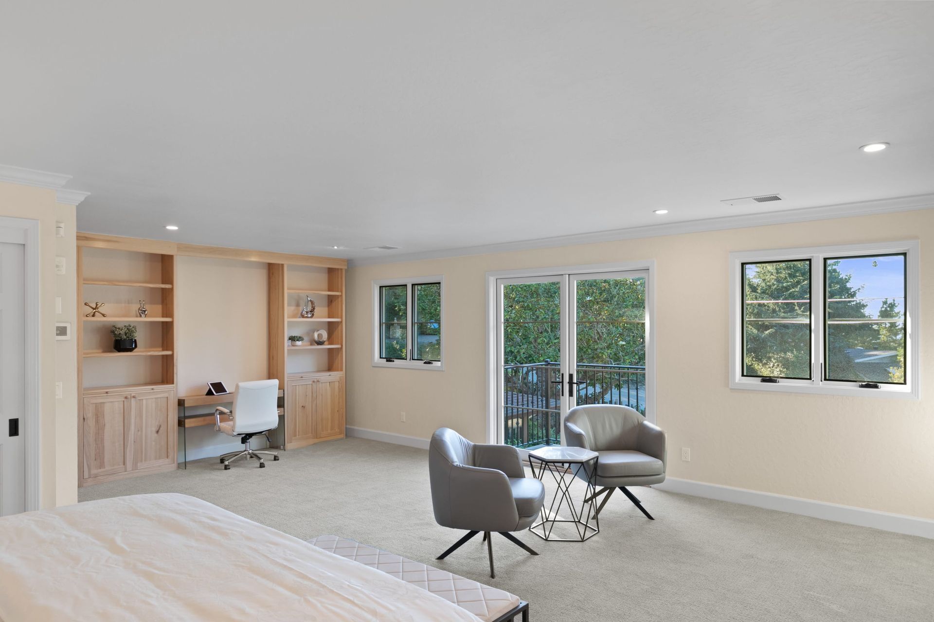 A large room with a bed , chairs , desk and sliding glass doors.