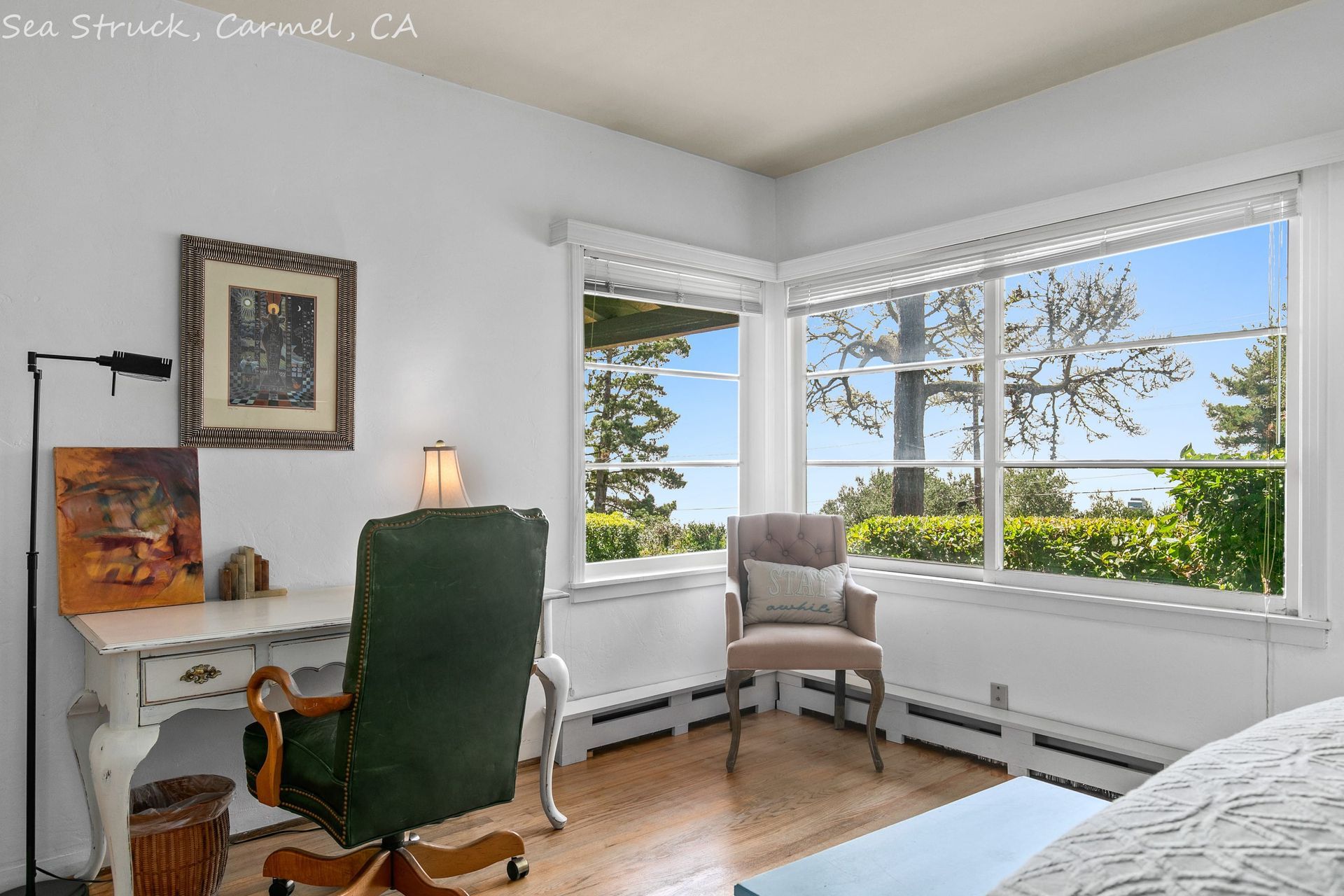 A bedroom with a desk and chair and a large window