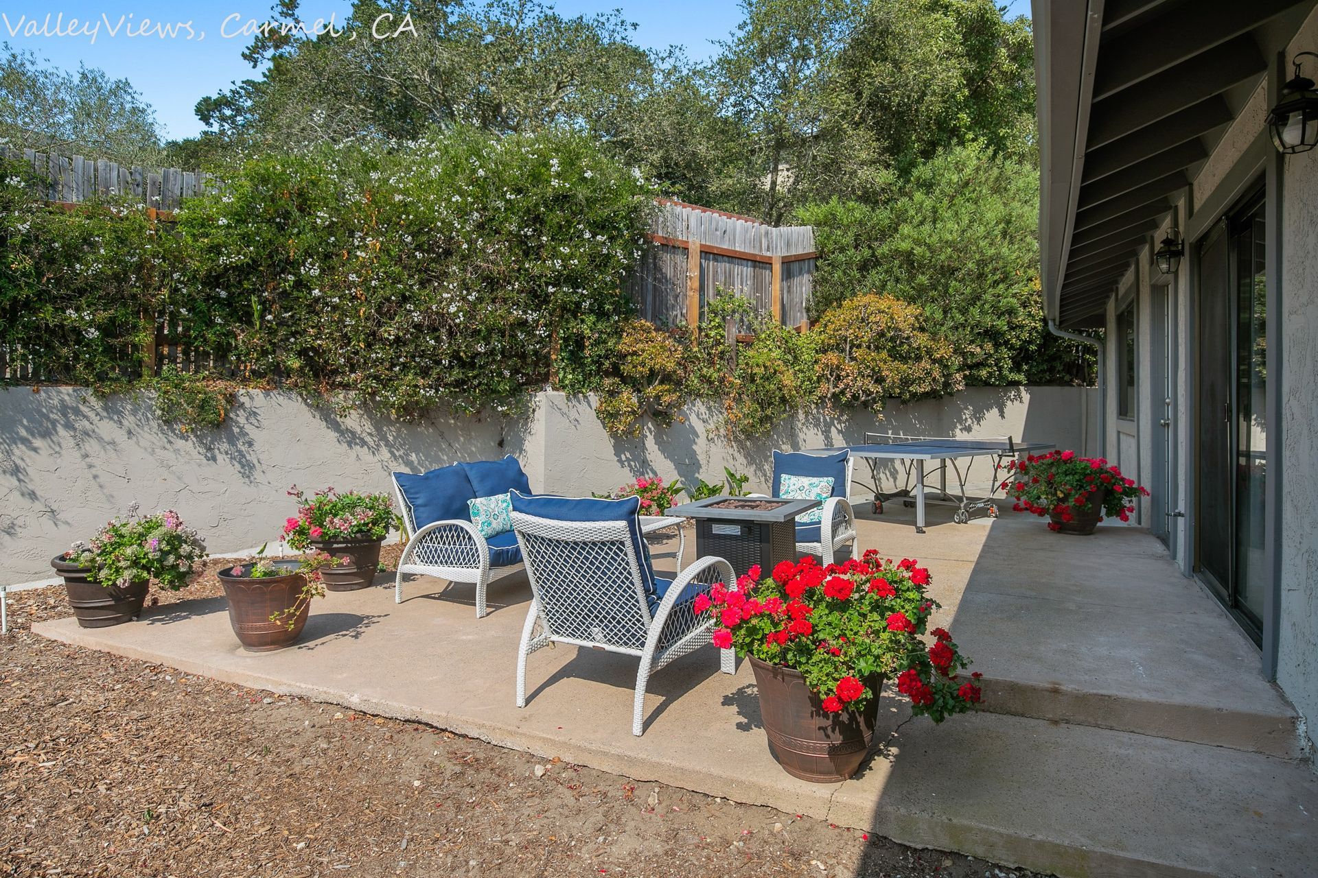 A patio with chairs and flowers in front of a house