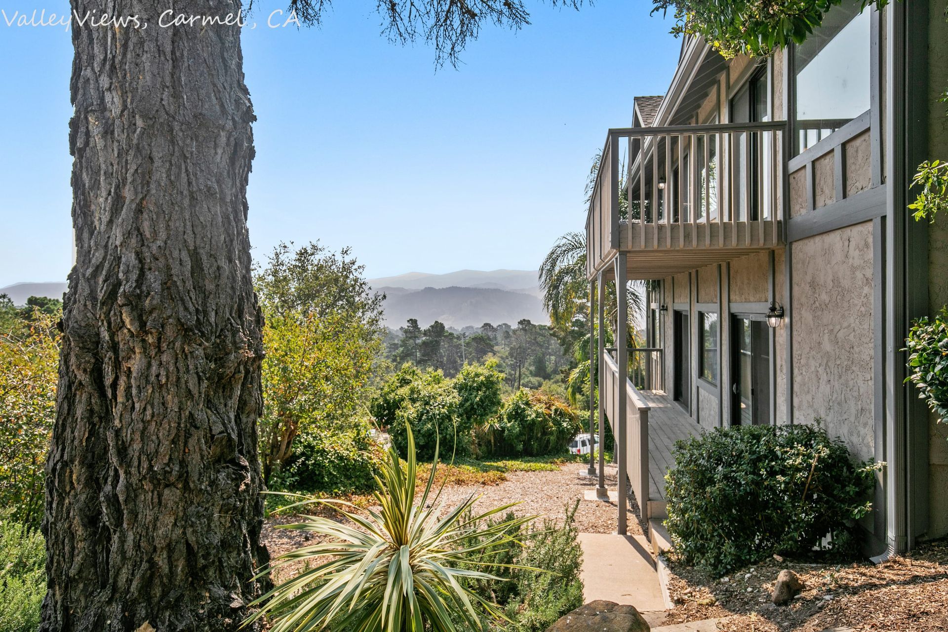 A house with a balcony and a tree in front of it
