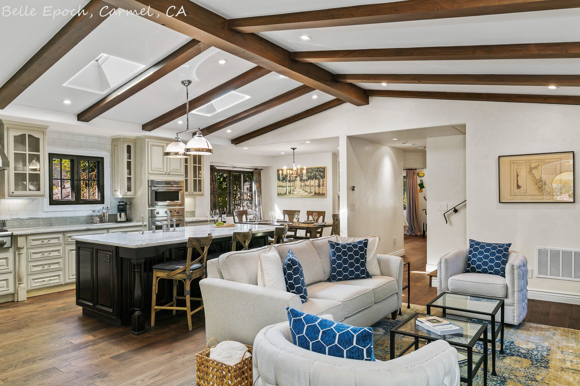 A living room with a couch and chairs and a kitchen