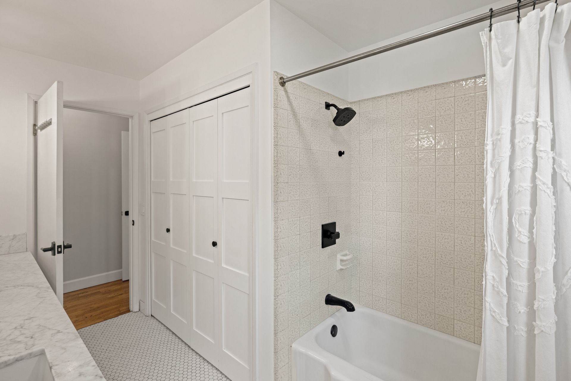 A bathroom with a bathtub , shower , sink and closet.
