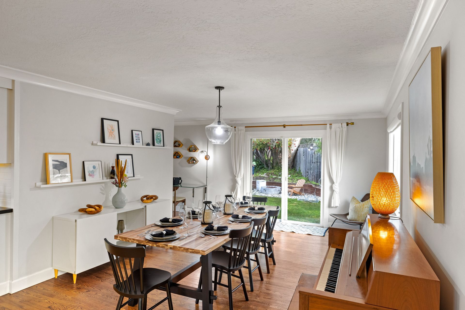 A dining room with a long table and chairs and a piano.