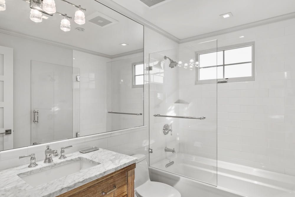 A bathroom with a sink , toilet , shower and window.