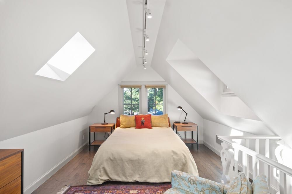 A bedroom with a large bed and a skylight in the ceiling.