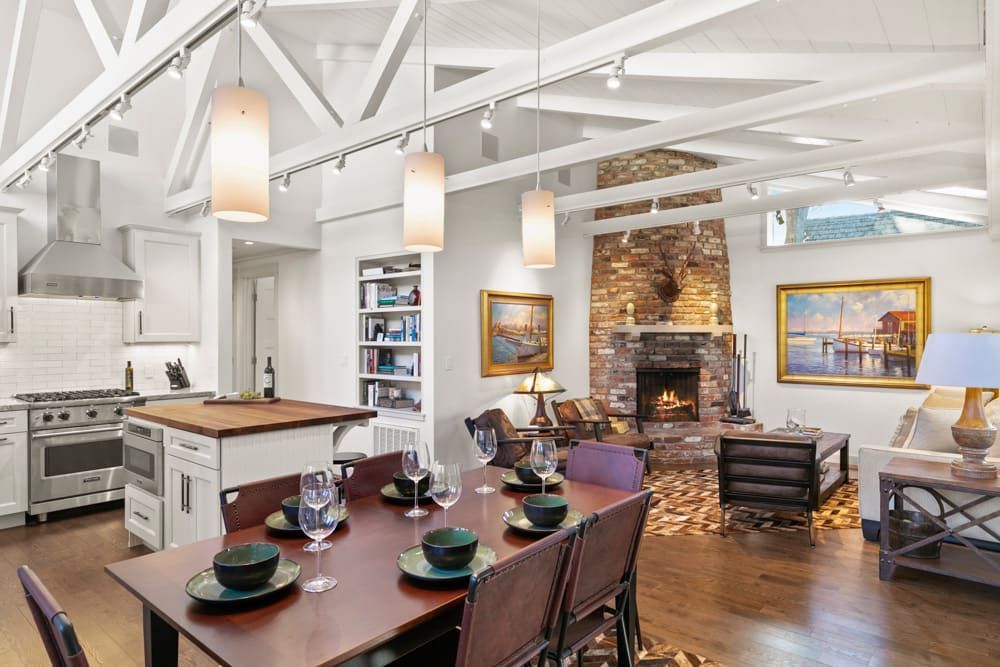 A living room with a dining table and chairs and a fireplace.