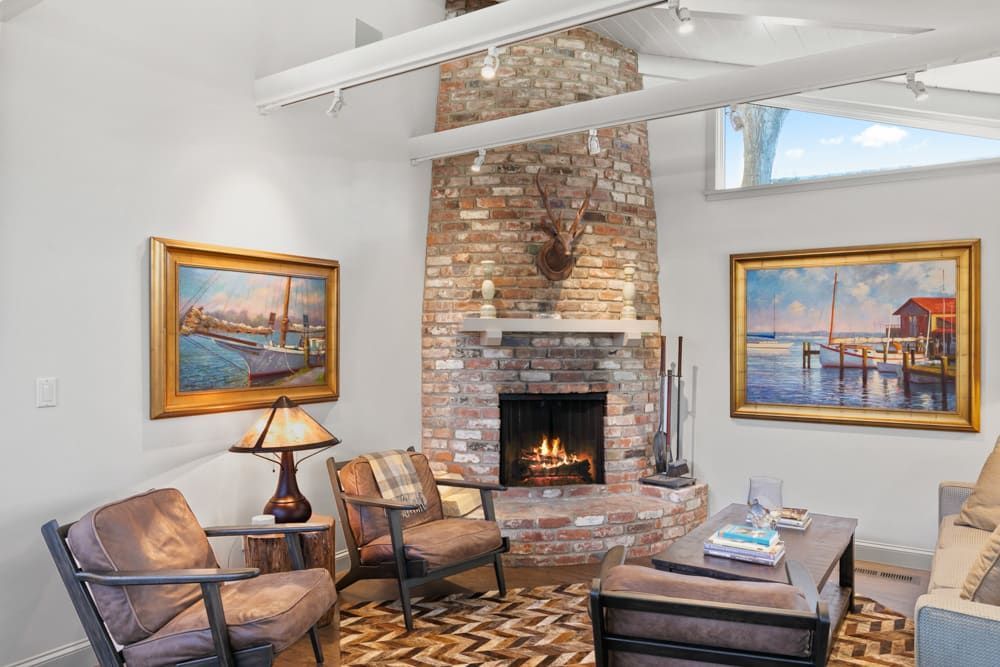 A living room with a fireplace and two paintings on the wall.