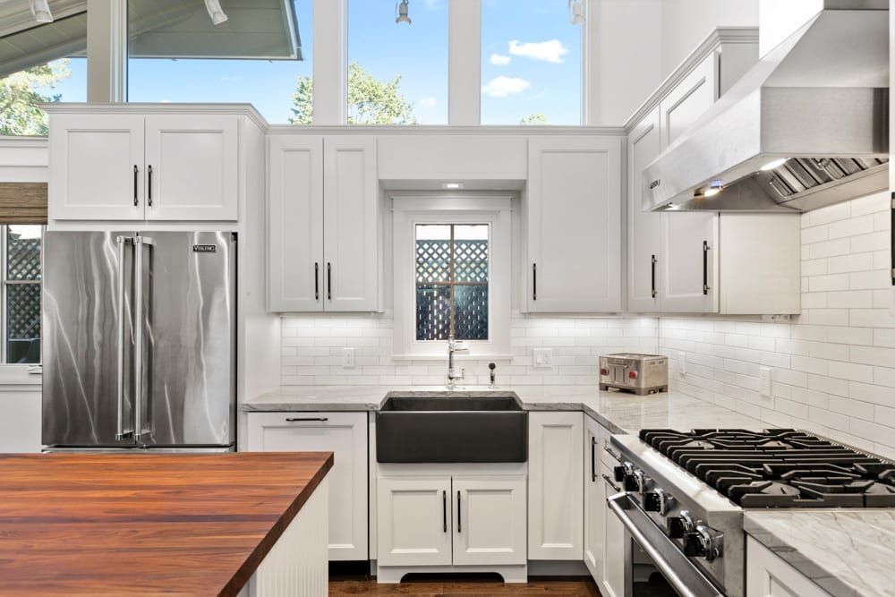 A kitchen with white cabinets , stainless steel appliances , a stove and a sink.