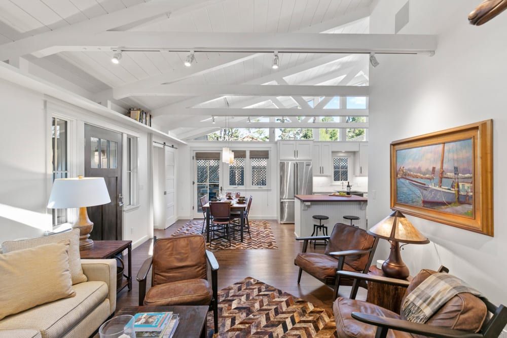 A living room with a couch , chairs , lamps and a painting on the wall.