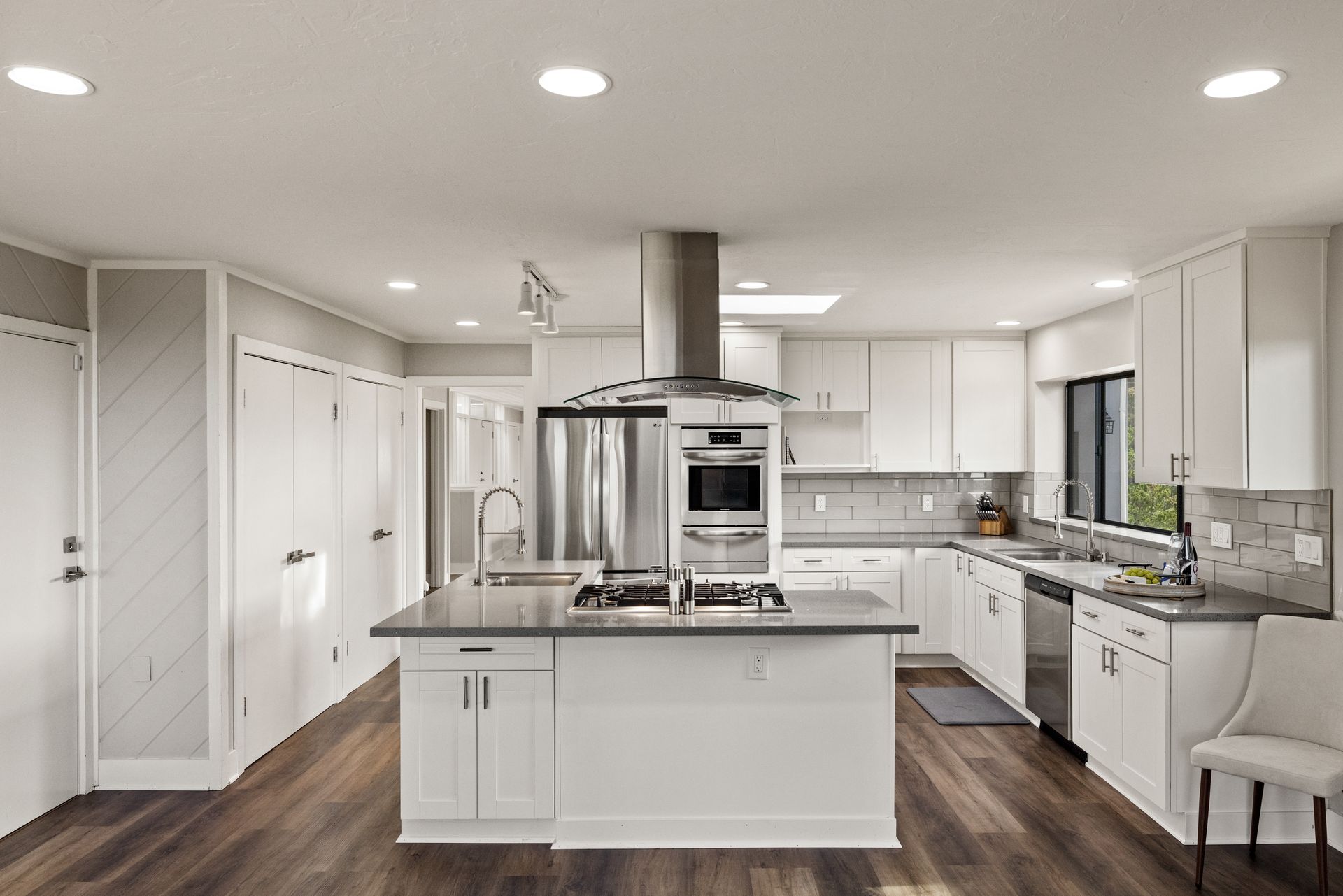 A kitchen with white cabinets , stainless steel appliances , and a large island.