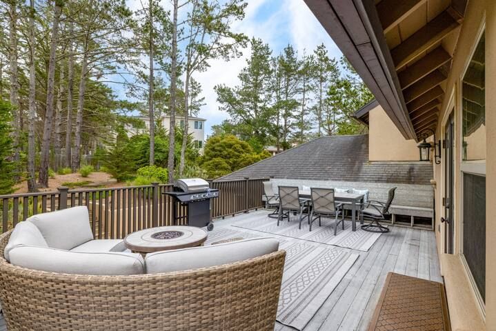 A large deck with a couch , table , chairs and a grill.