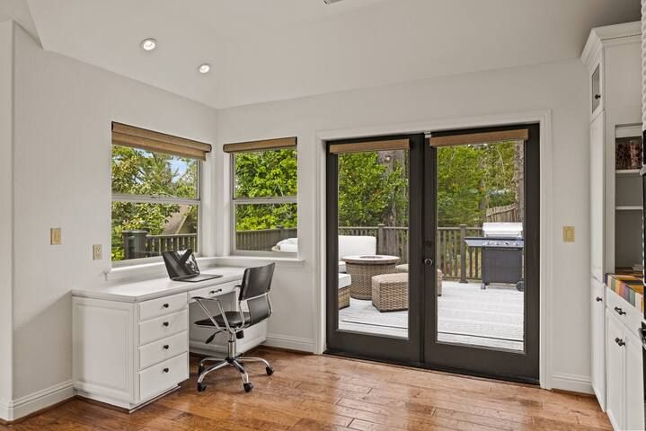 A room with a desk , chair and sliding glass doors leading to a deck.