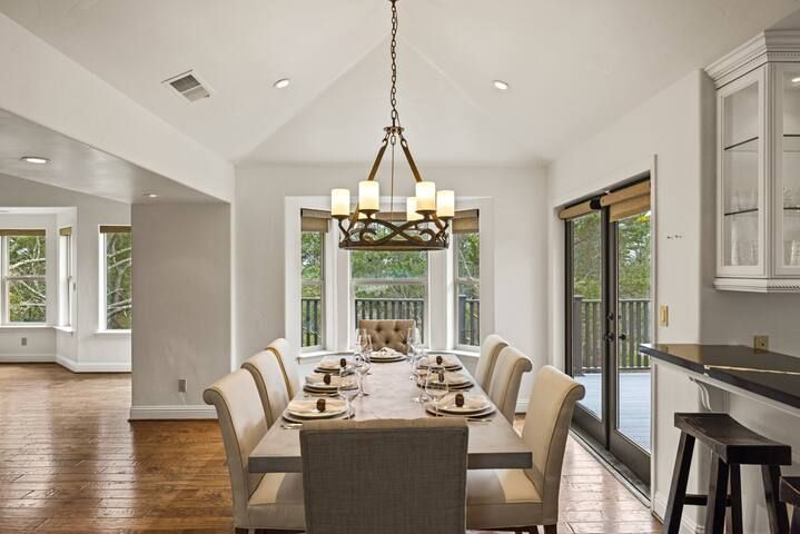A dining room with a long table and chairs and a chandelier hanging from the ceiling.