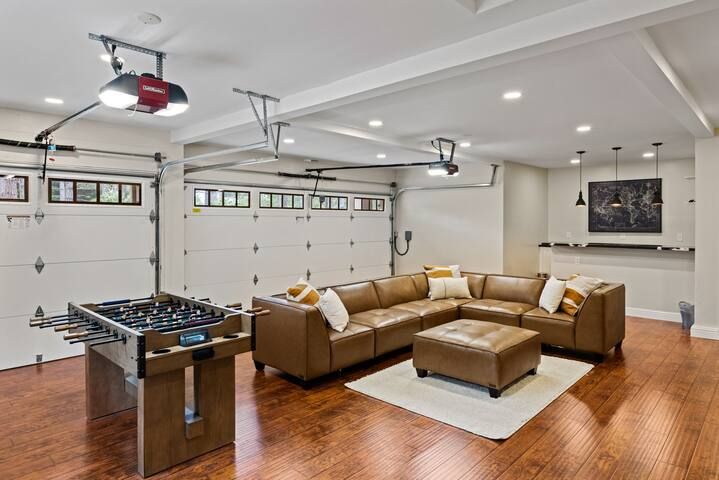 A living room with a couch and a foosball table in a garage.