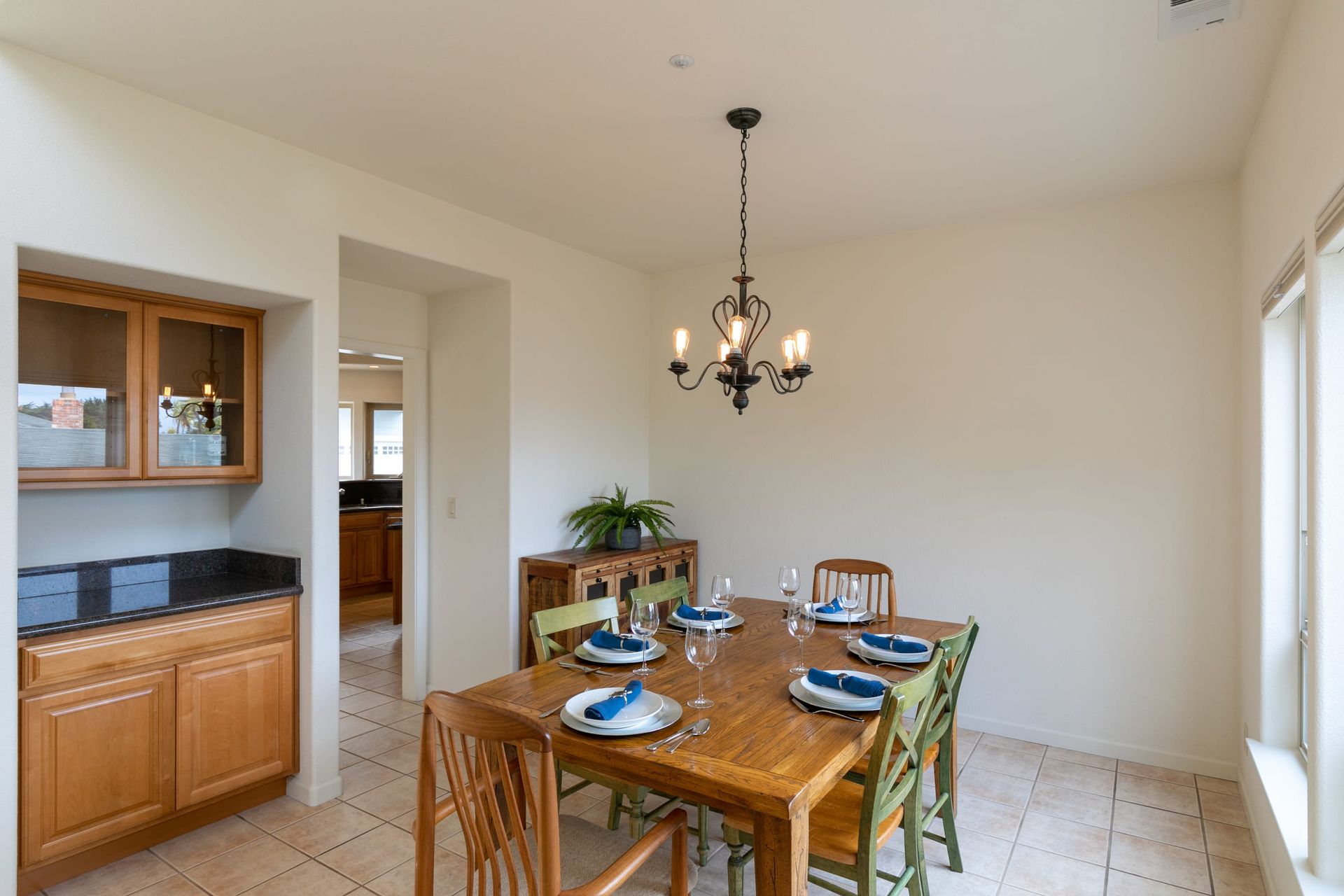 A dining room with a wooden table and chairs and a chandelier.