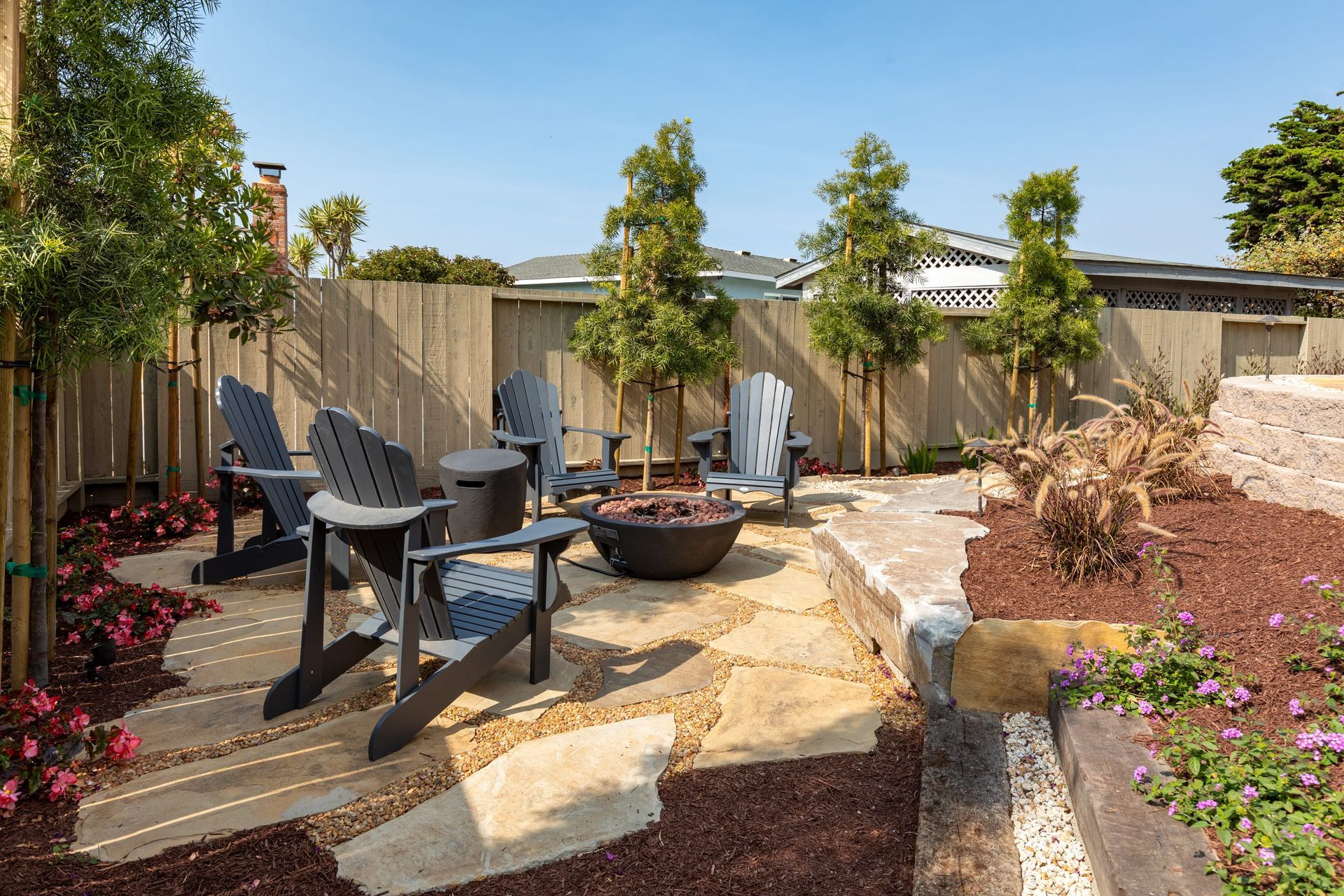 A patio with chairs and a fire pit in the middle of it.