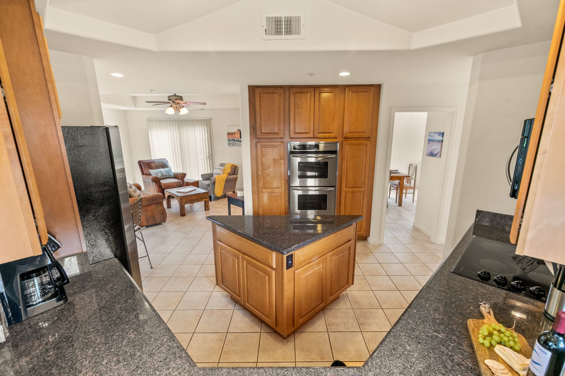 A kitchen with a large island in the middle and a living room in the background.