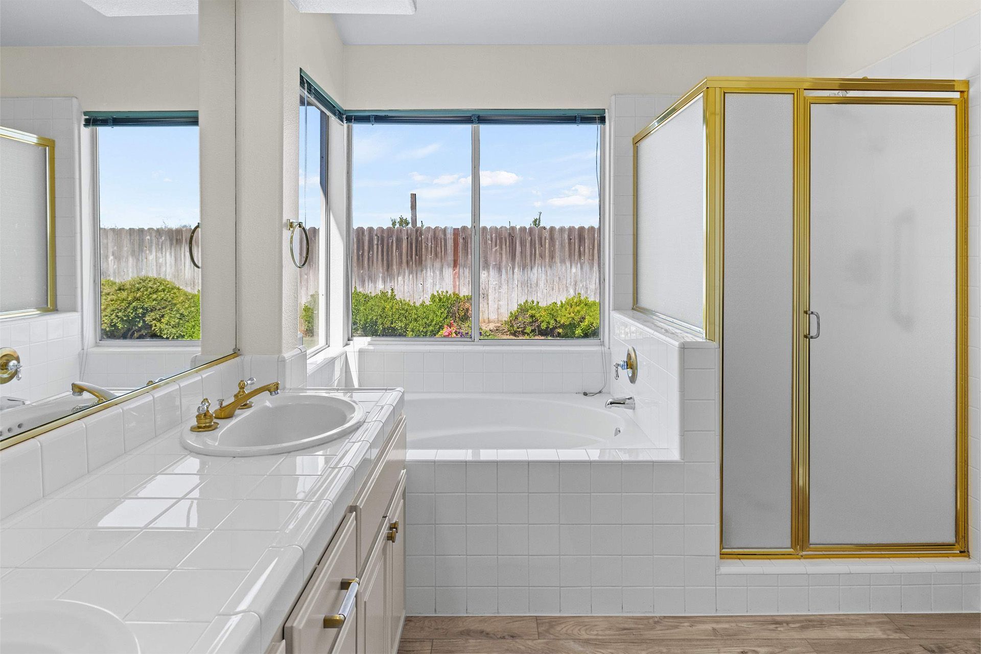 A bathroom with a tub , sink , mirror and shower.