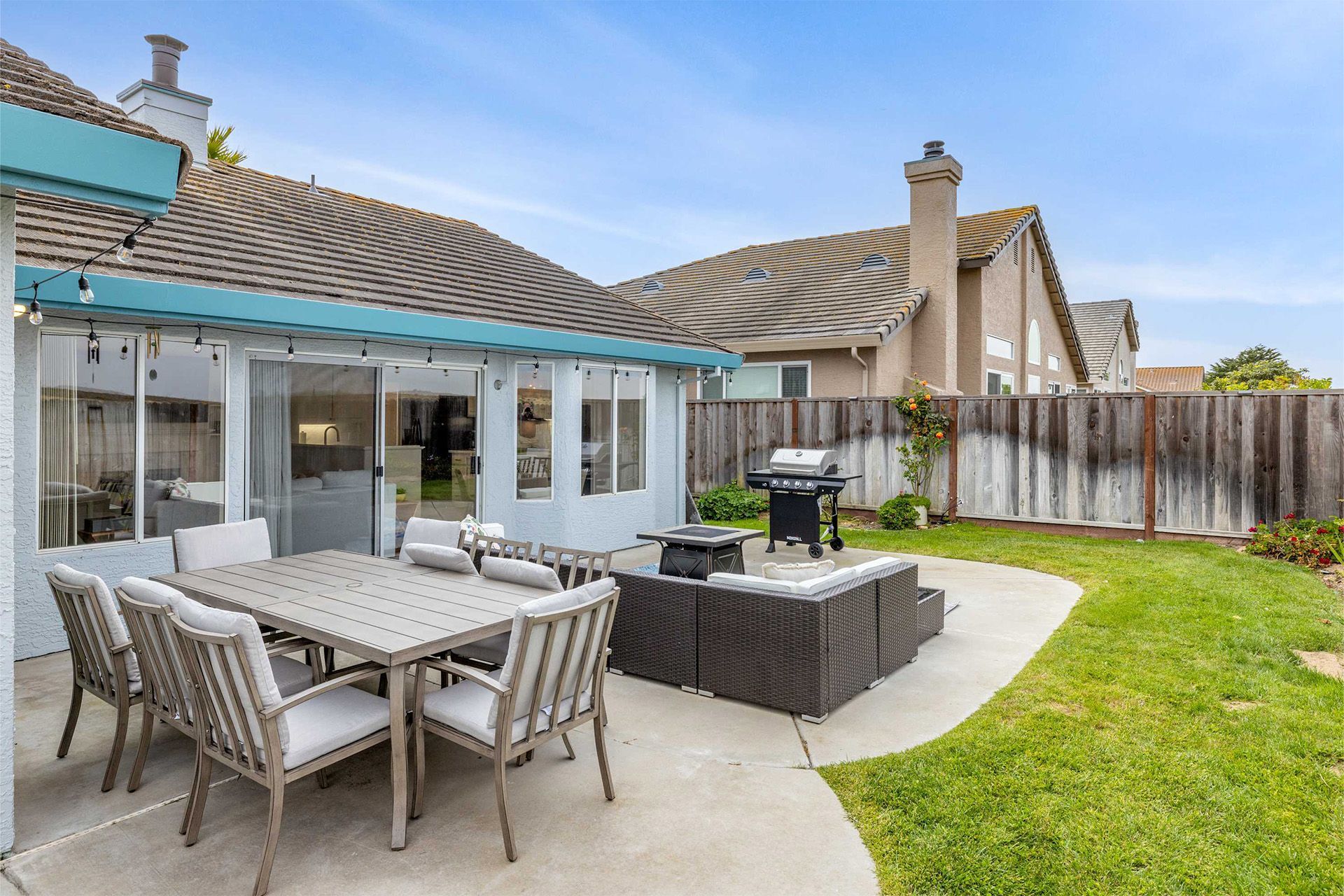 A patio with a table and chairs and a grill in the backyard of a house.