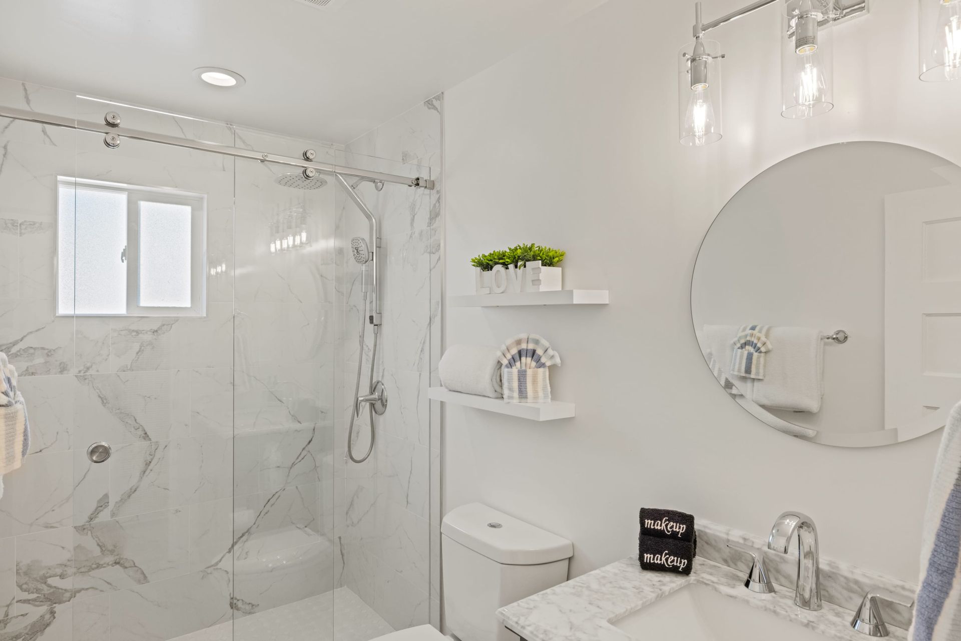 A bathroom with a sink , toilet , shower and mirror.