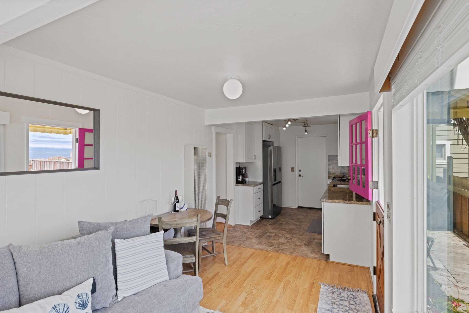 A living room with a couch , table , chairs and a mirror.