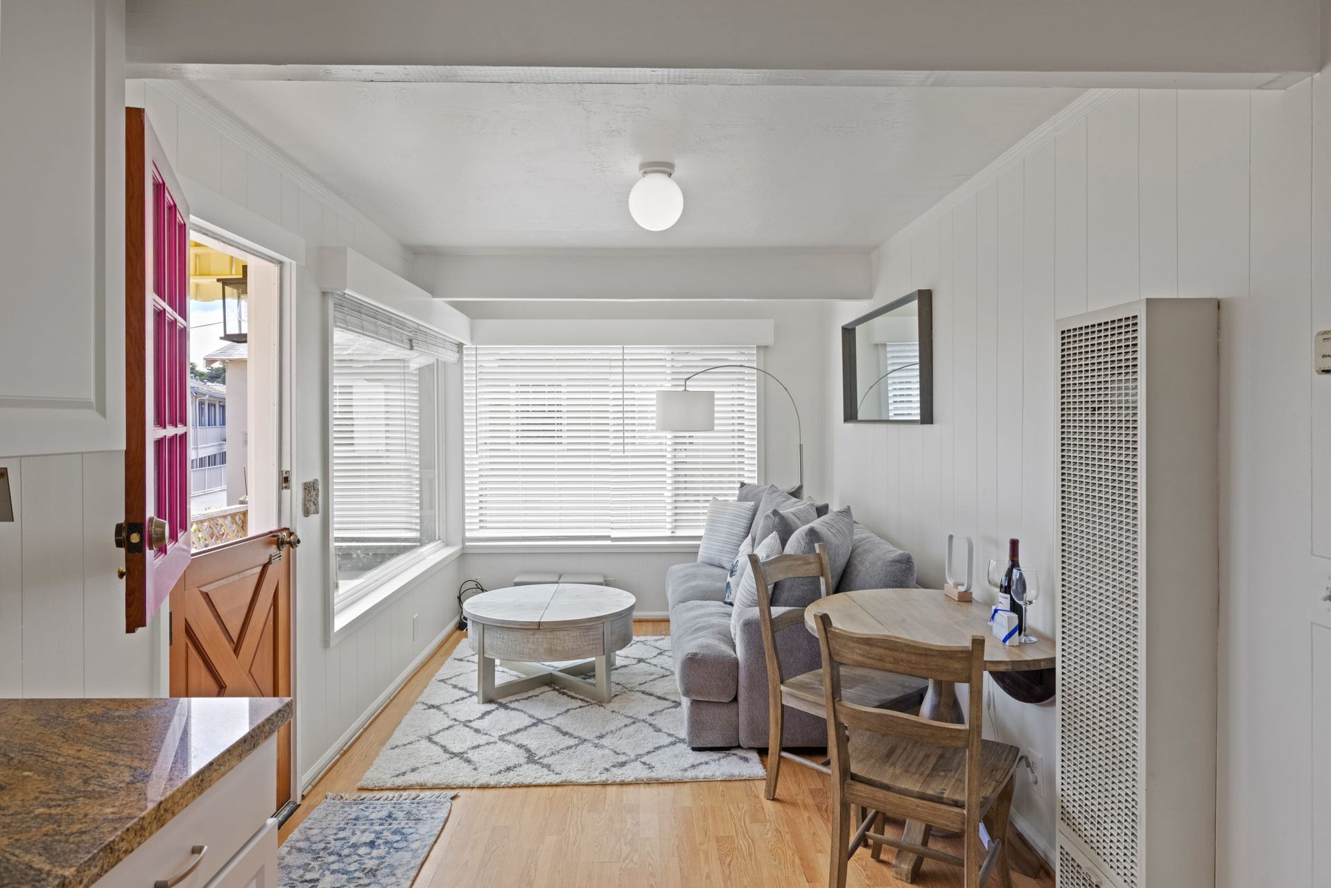 A living room with a couch , table , chairs and a window.