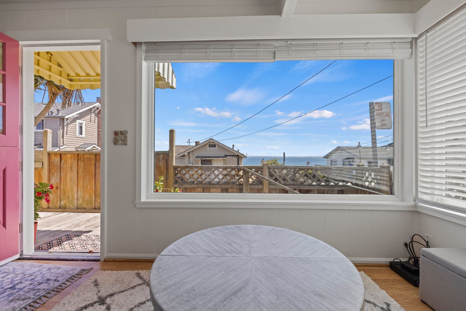A yellow house with a pink door and a wooden fence