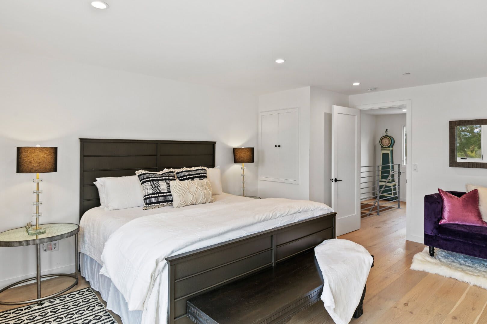 A bedroom with a large bed and a purple chair