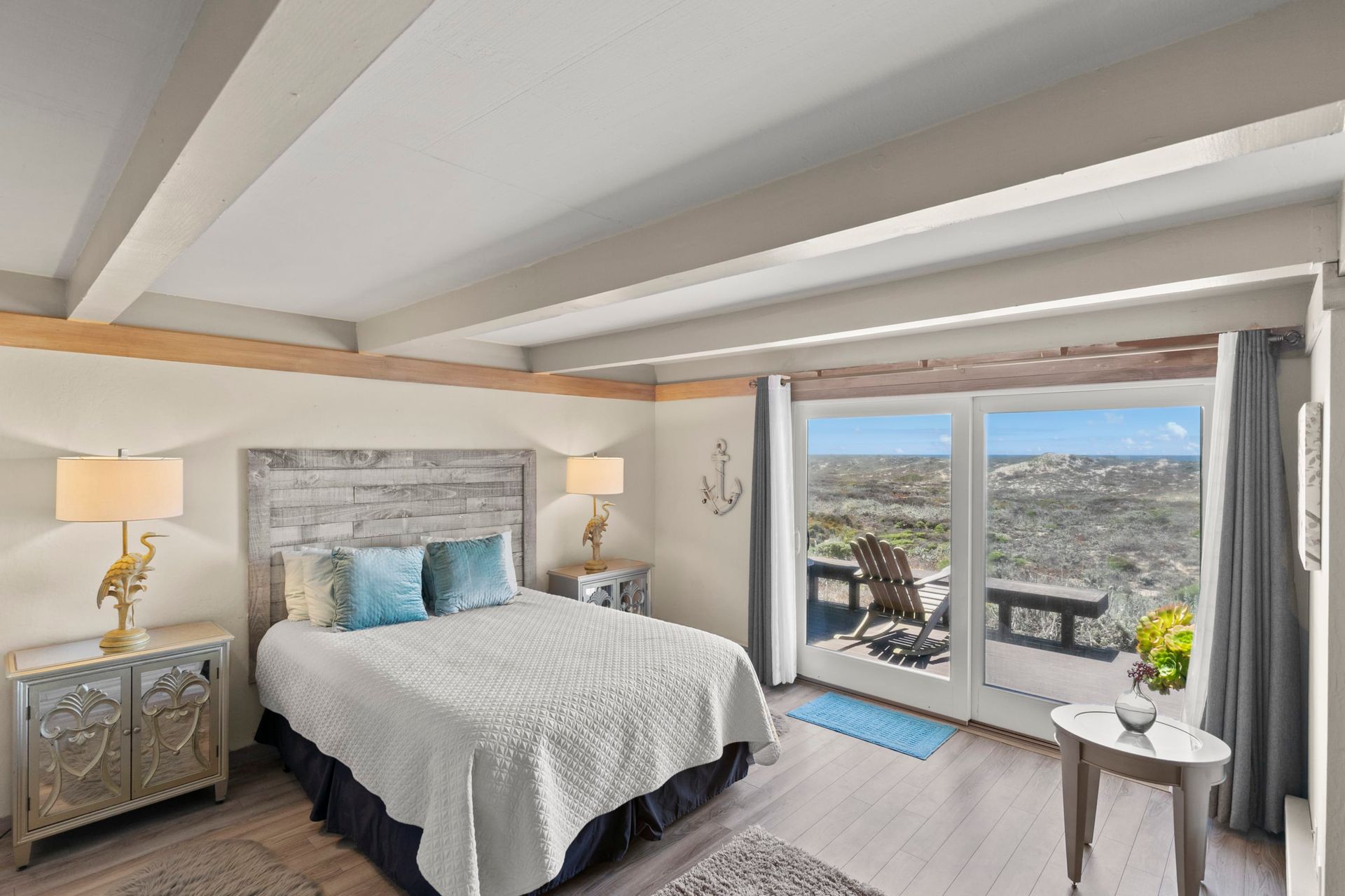 A bedroom with a king size bed and a large window with a view of the ocean.
