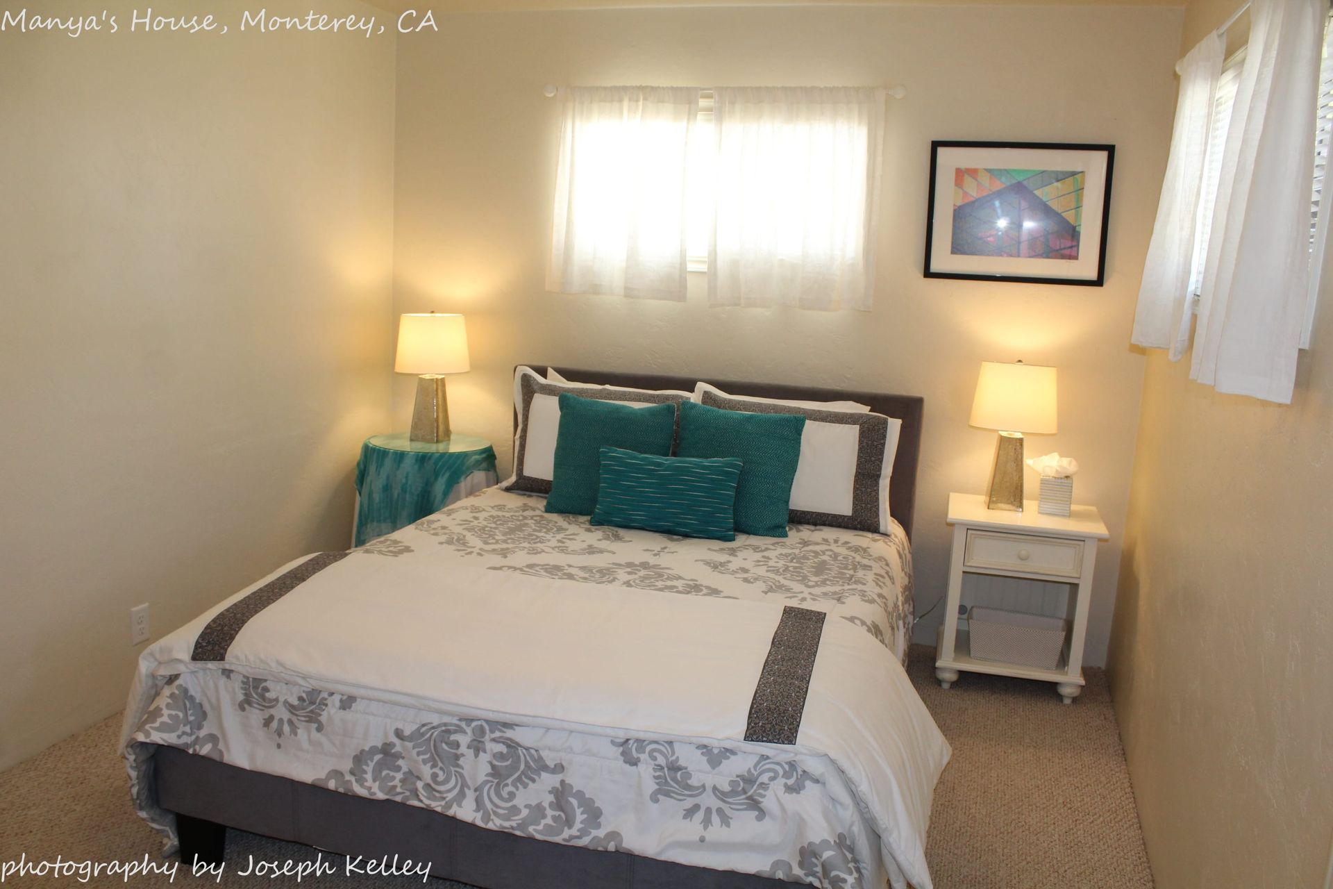 A bedroom with a bed , nightstand , lamps and a picture on the wall.