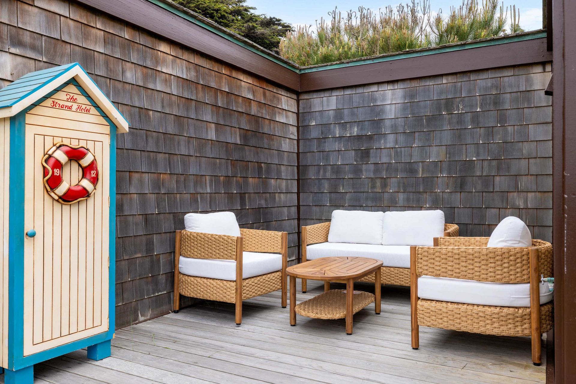 A patio with wicker furniture and a life preserver on the door.