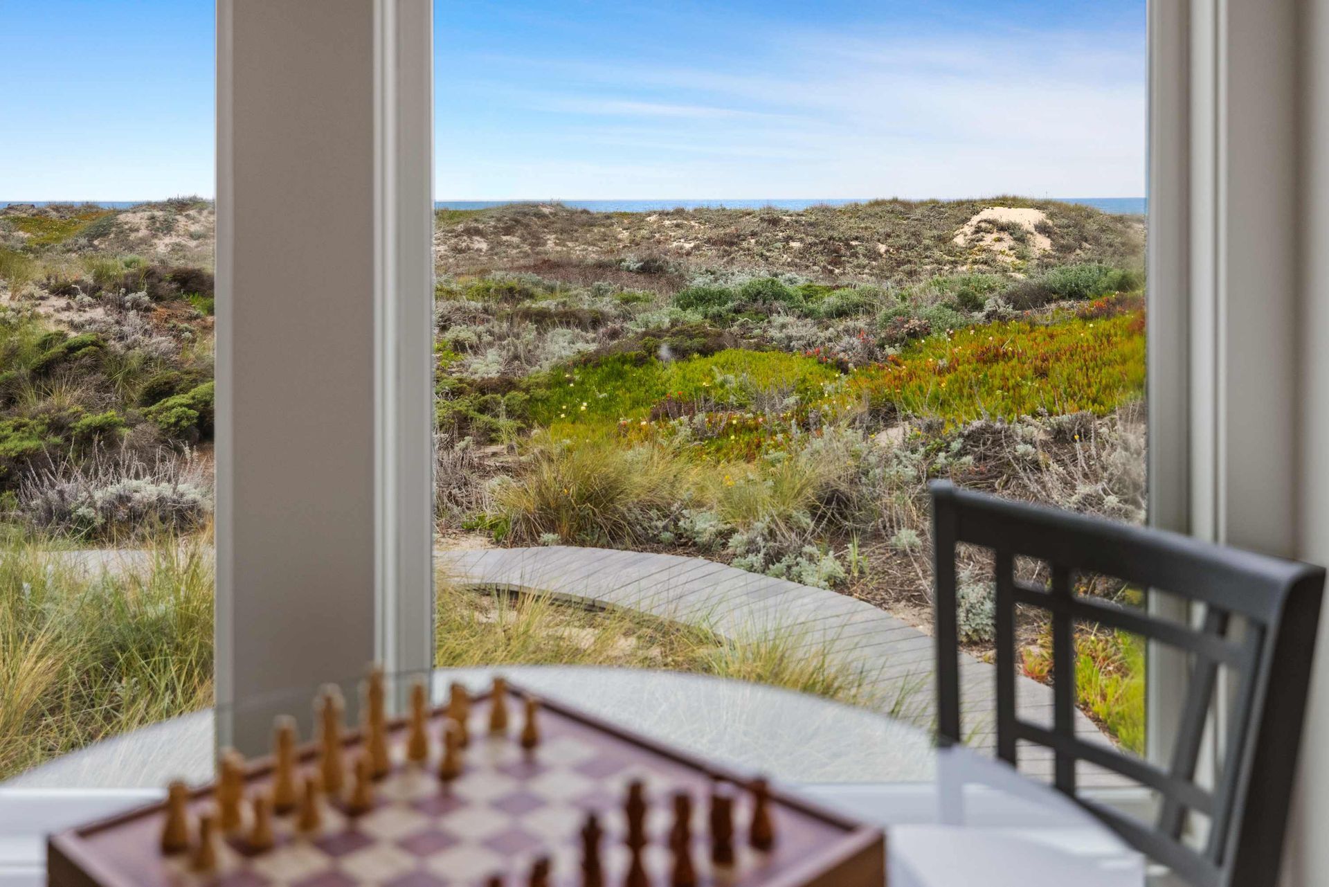 A chess board is sitting on a table in front of a window.