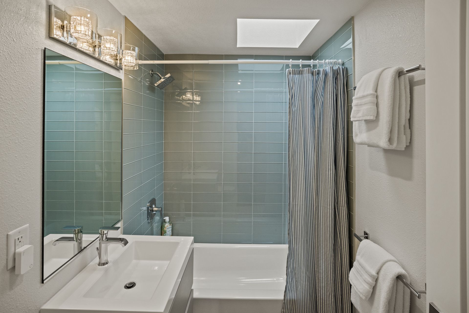 A bathroom with a sink , tub , shower and mirror.