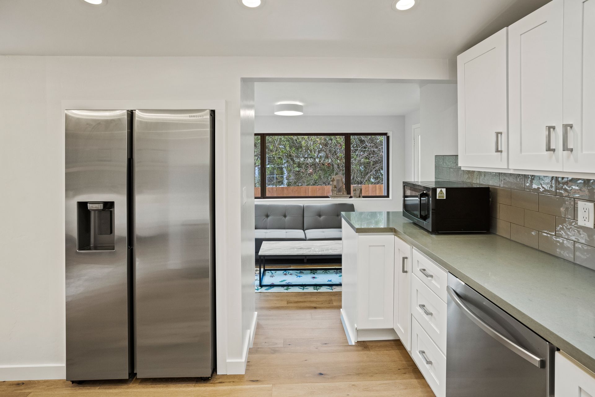 A kitchen with a stainless steel refrigerator and white cabinets.