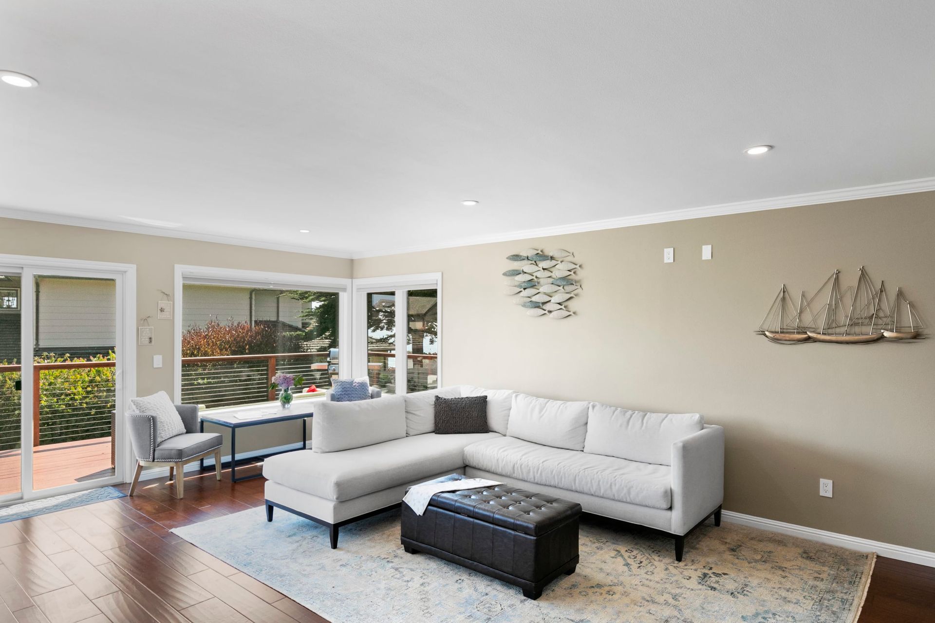 A living room with a sectional couch , ottoman , table and chairs.
