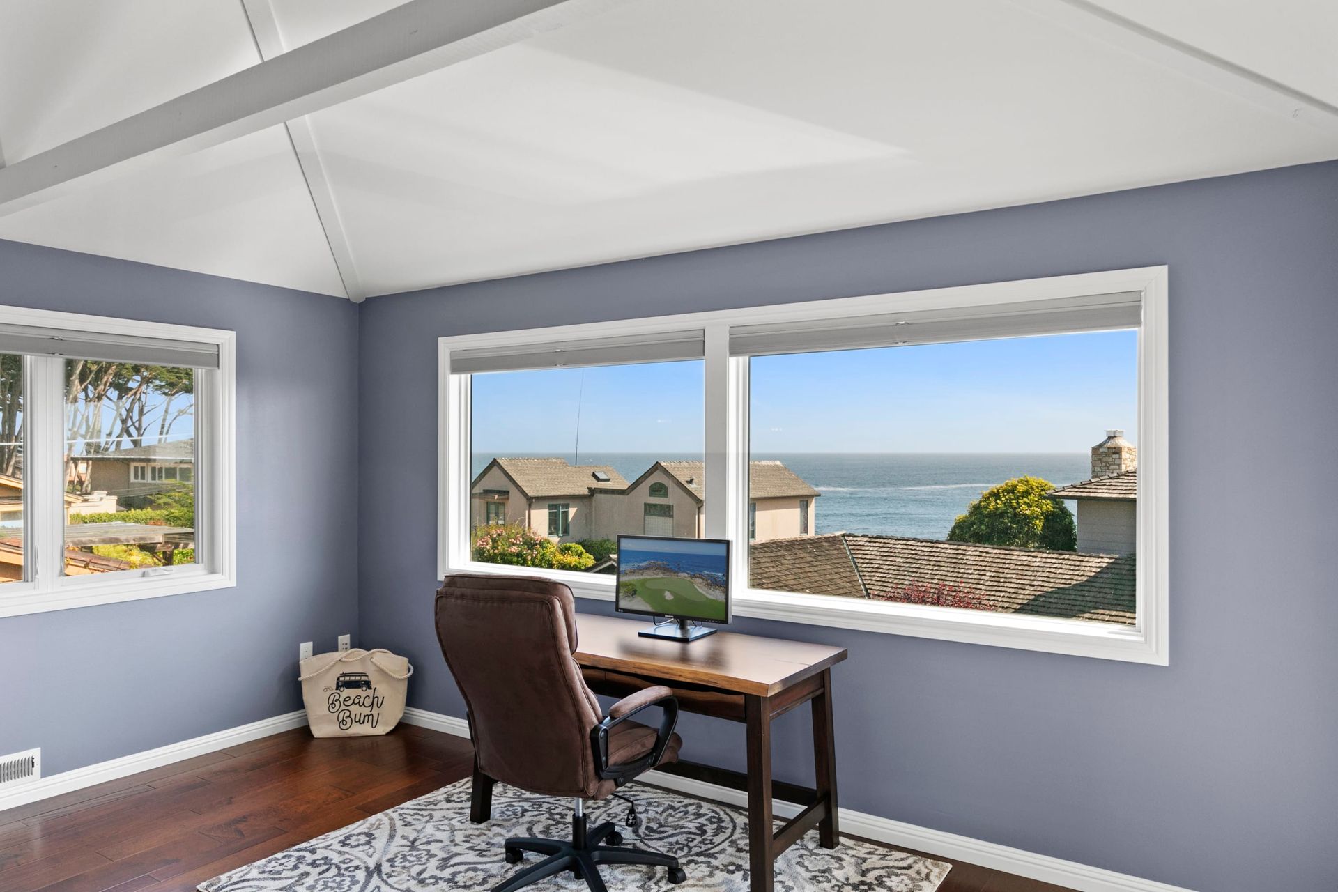 A home office with a desk and chair and a view of the ocean.