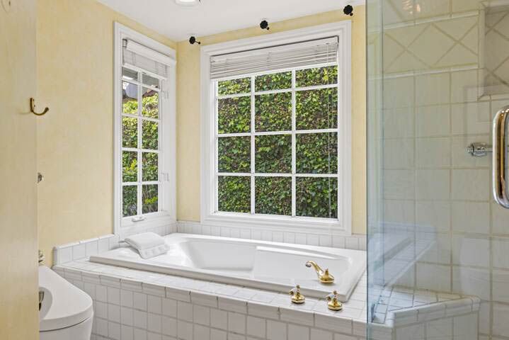 A bathroom with a tub , shower and window.