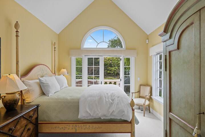 A bedroom with a bed , dresser , chair and window.