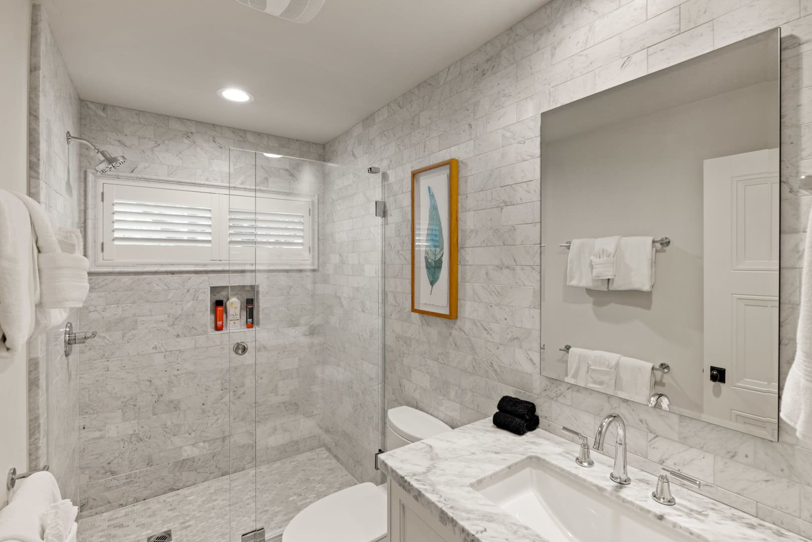 A bathroom with a walk in shower , sink , toilet and mirror.