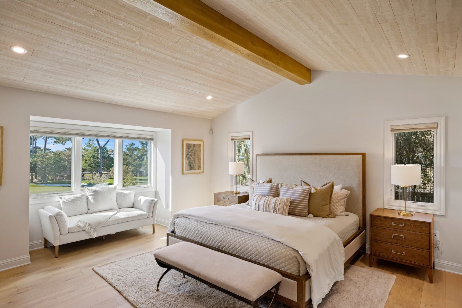 A bedroom with a bed , couch , nightstand and windows.