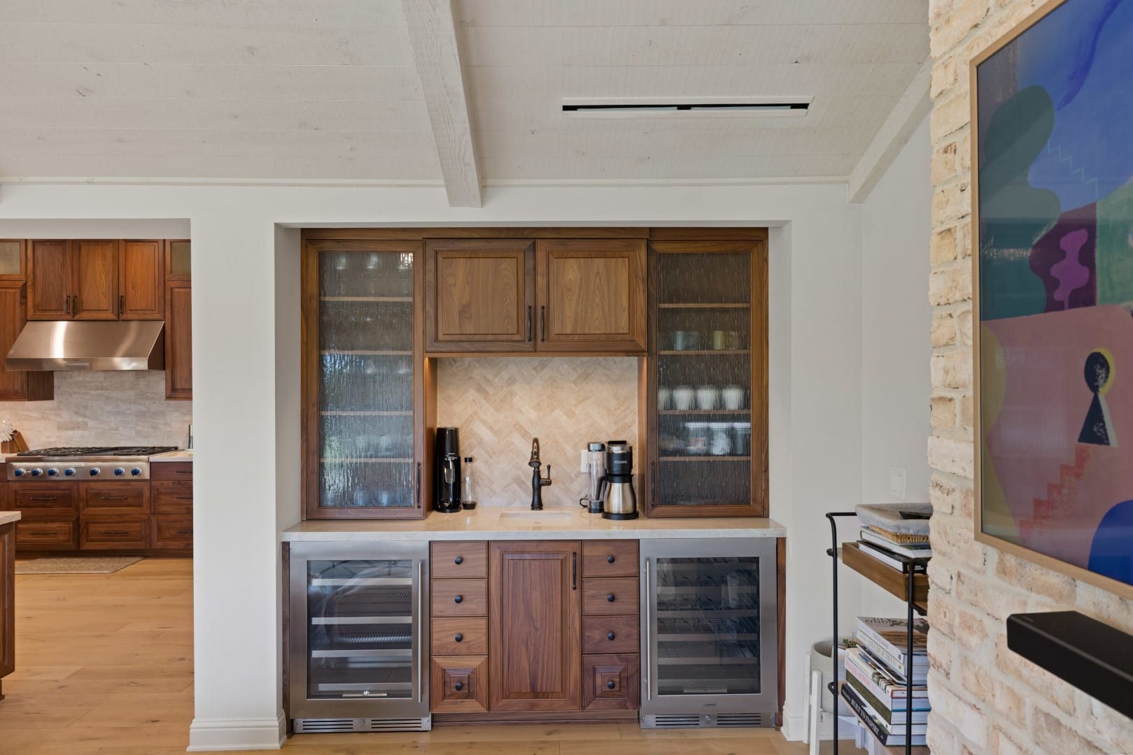 A kitchen with wooden cabinets , stainless steel appliances and a wine cooler.