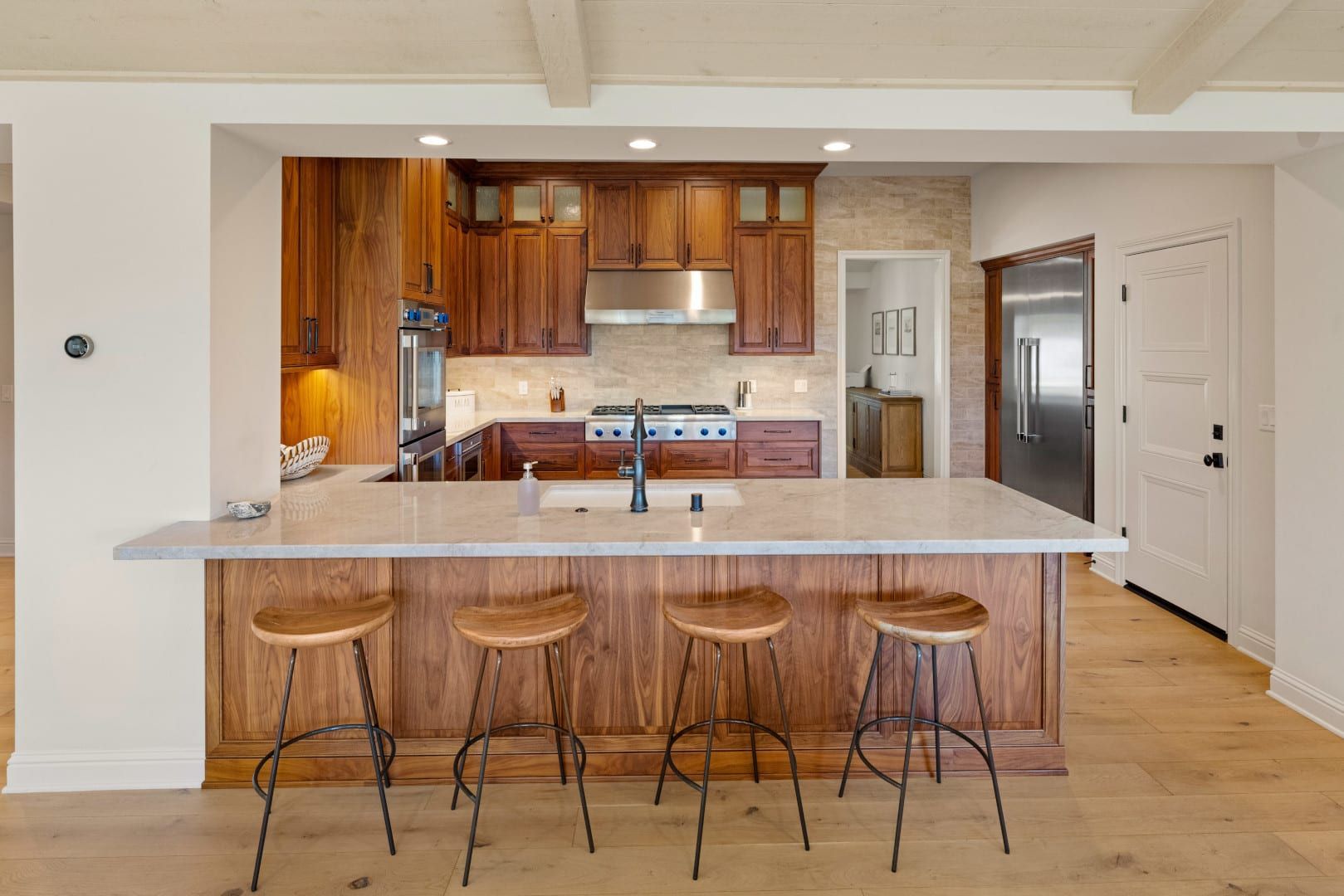 A kitchen with wooden cabinets and stools and a large island.