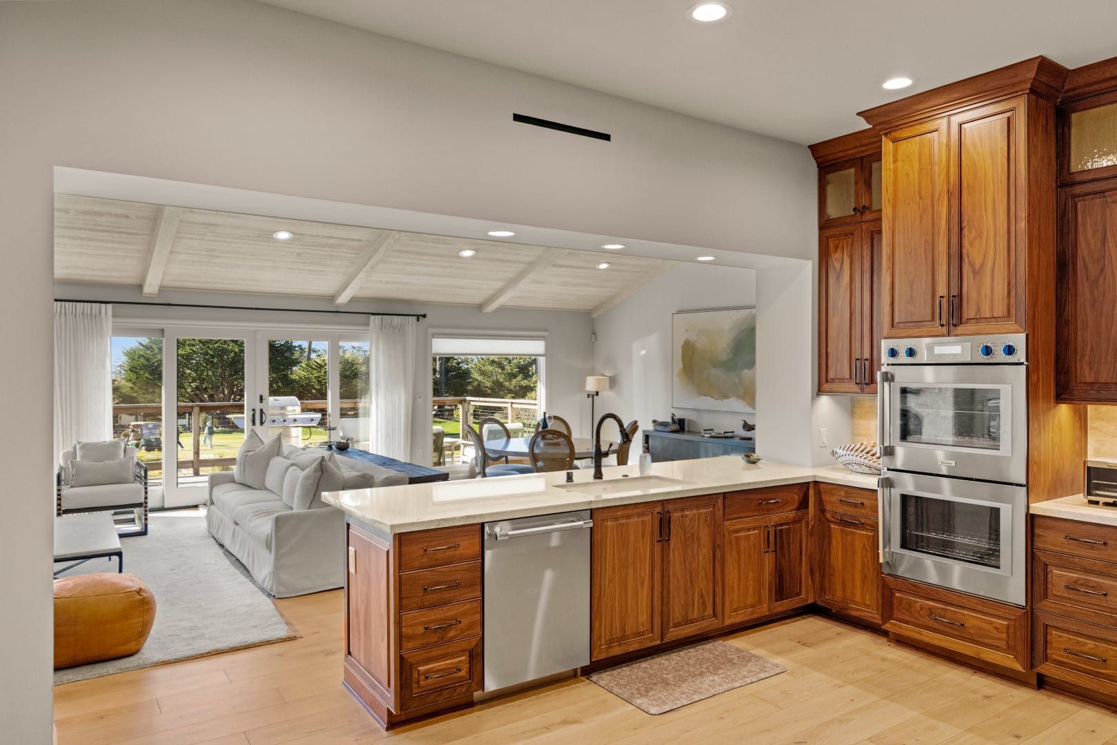 A kitchen with wooden cabinets and stainless steel appliances is open to a living room.