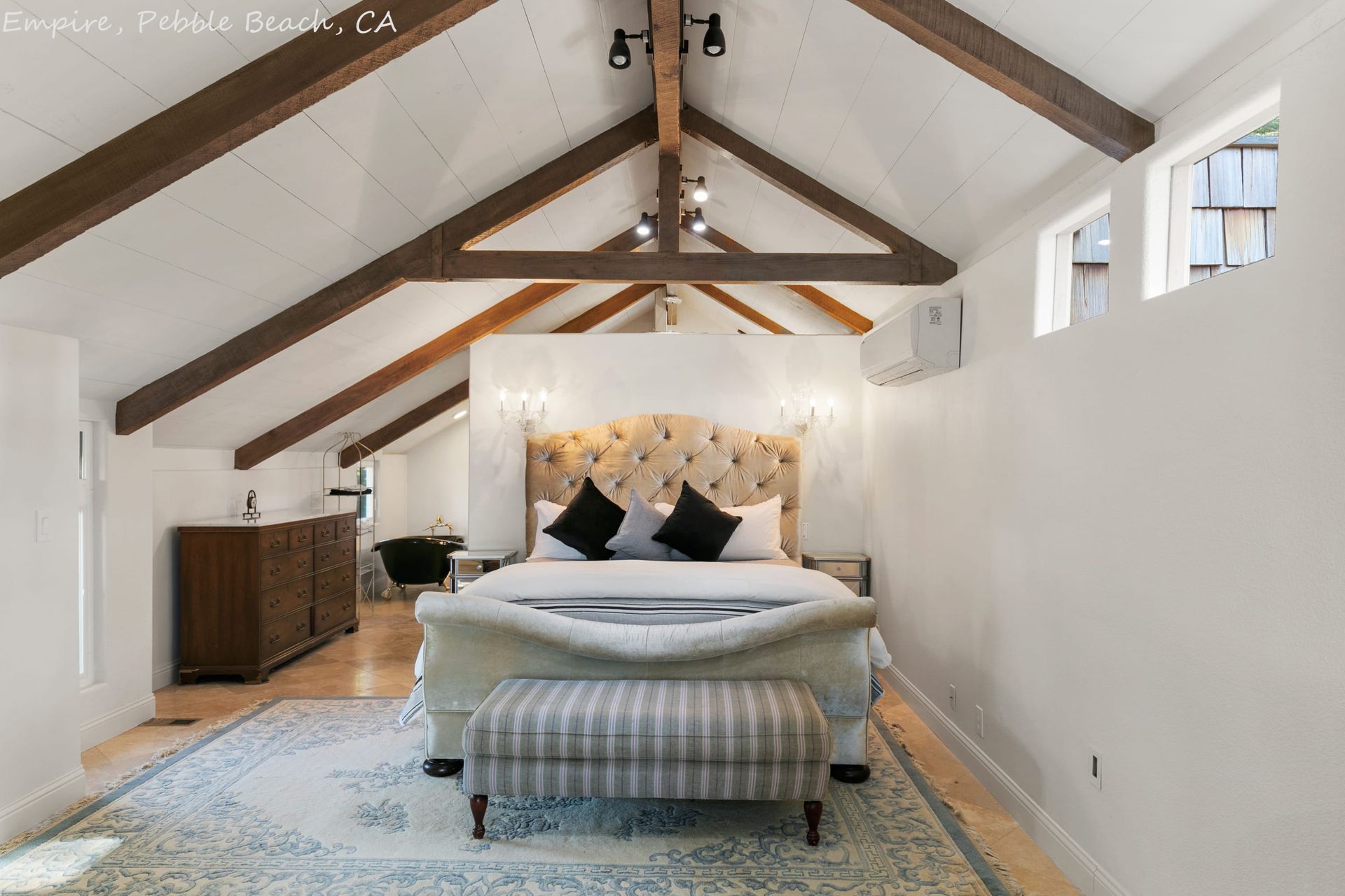 A bedroom with a king size bed and a bench.