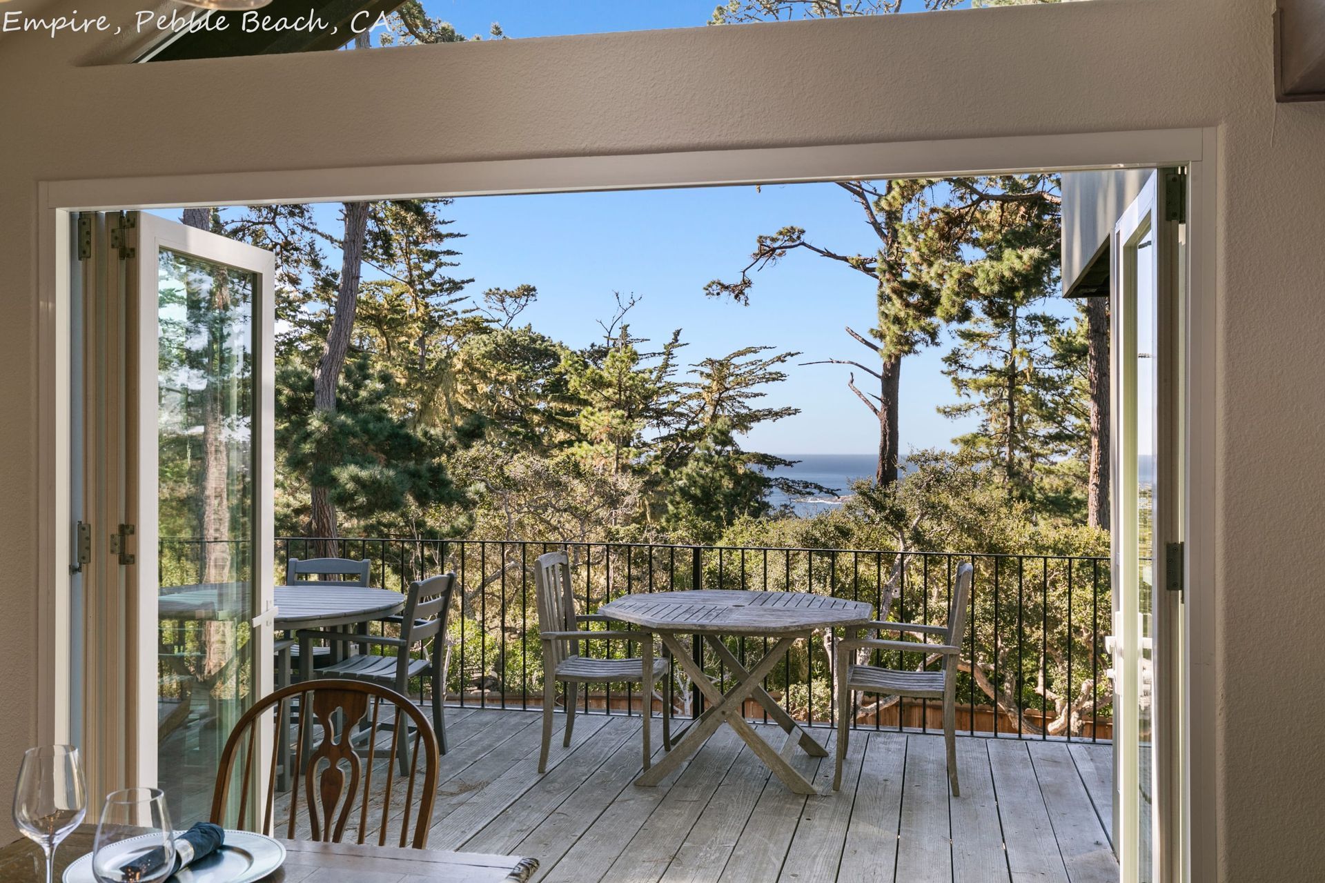 A table and chairs on a deck with a view of the ocean