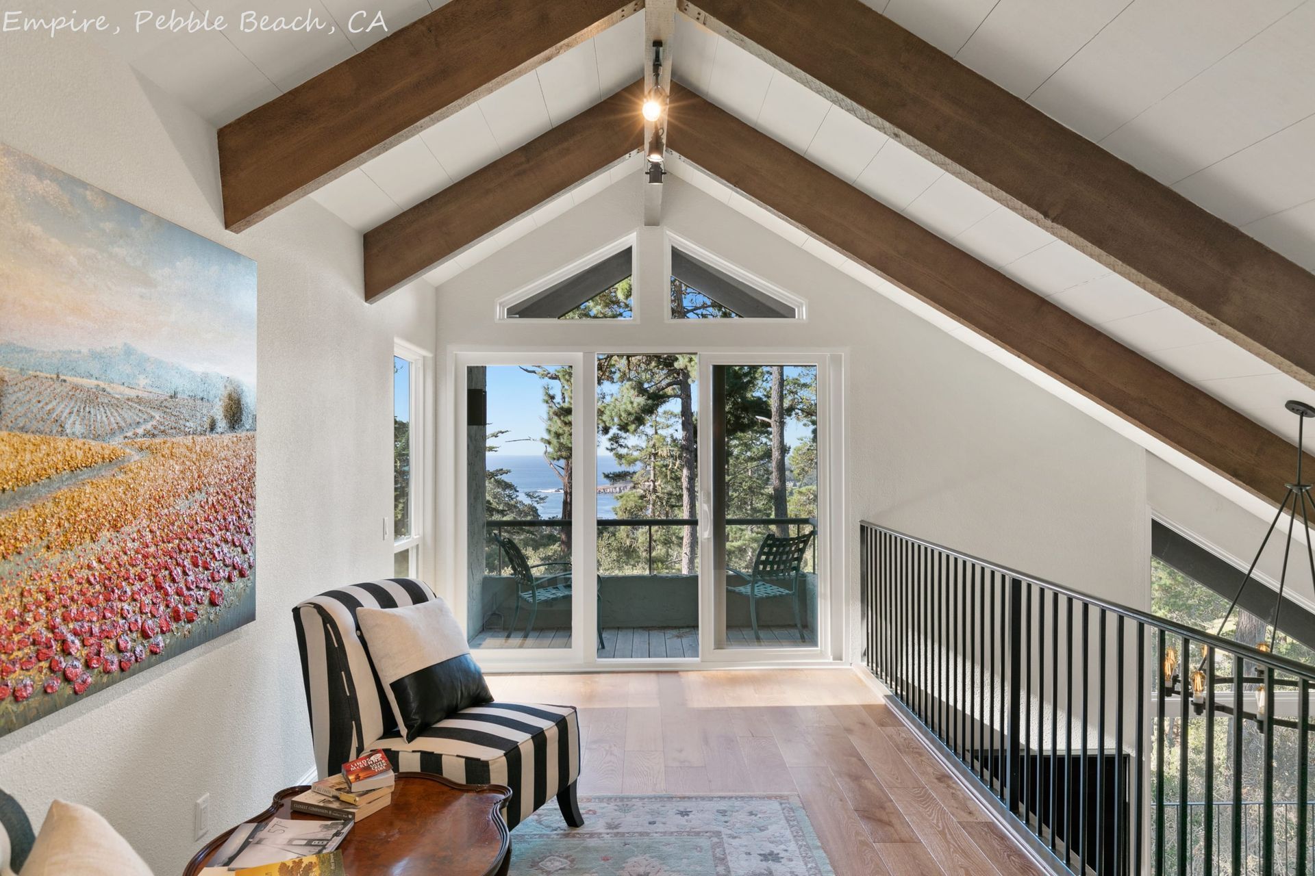 A living room with a balcony and a painting on the wall