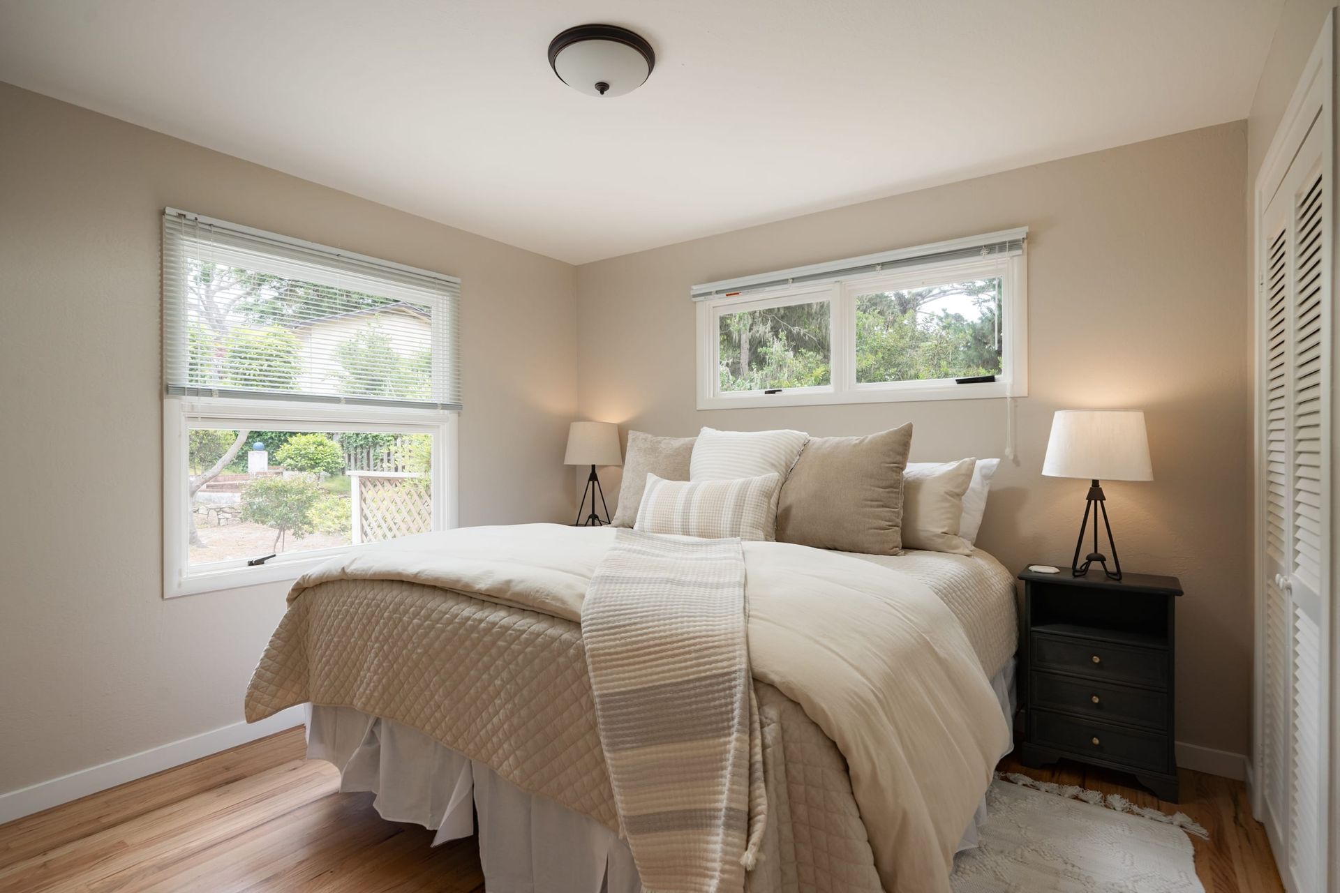 A bedroom with a king size bed and two windows