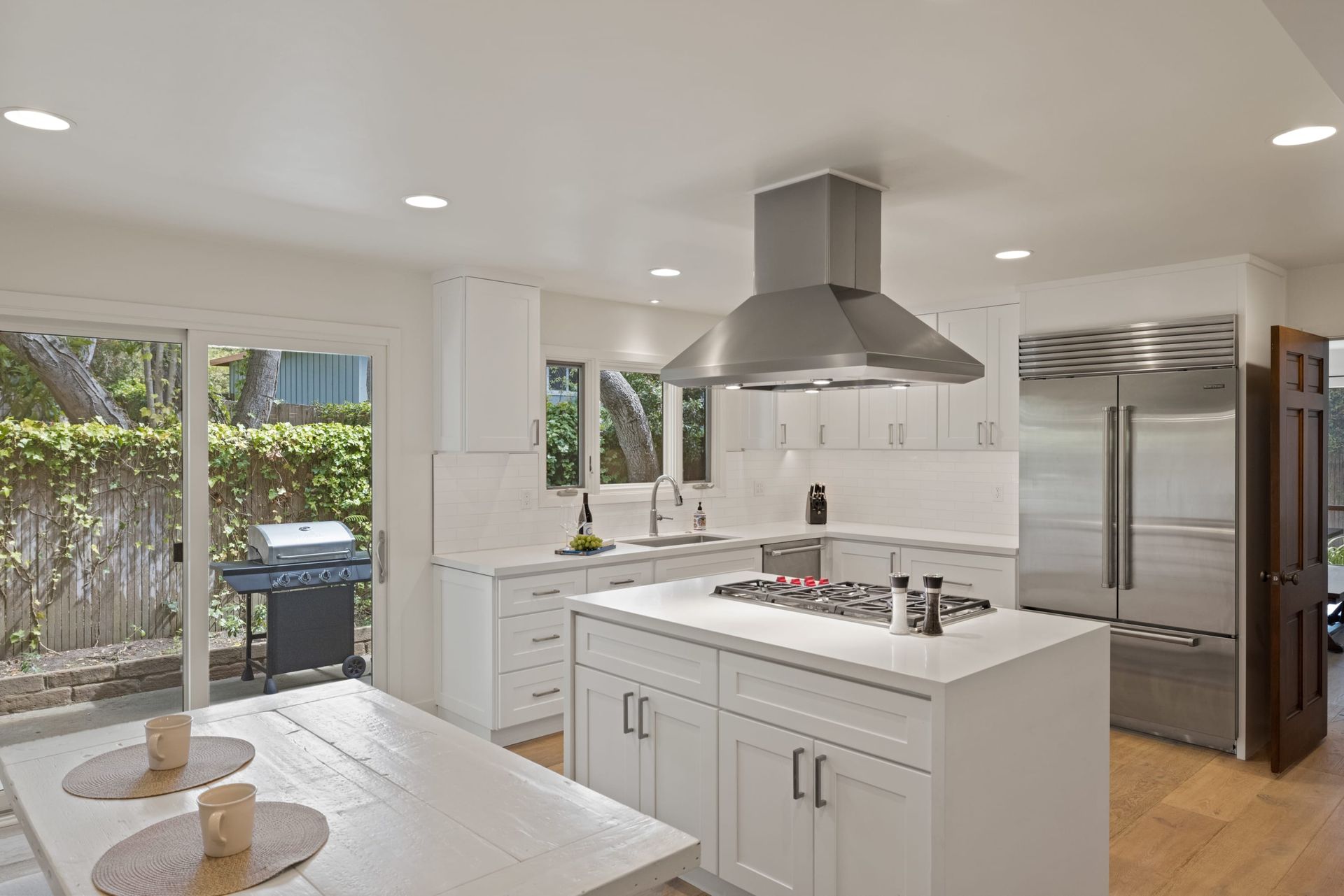 A kitchen with white cabinets , stainless steel appliances and a large island.