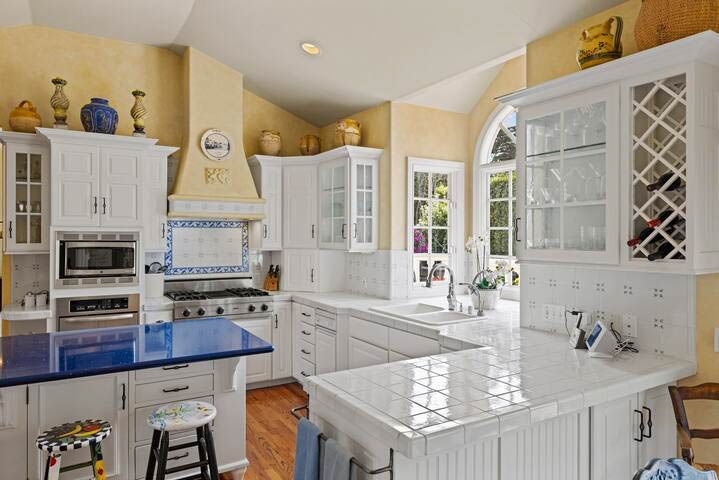 A kitchen with white cabinets and a blue counter top.